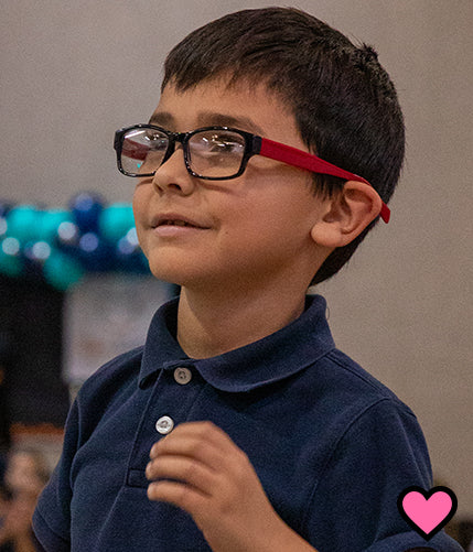 Boy looking through new pair of eyeglasses with smile on face
