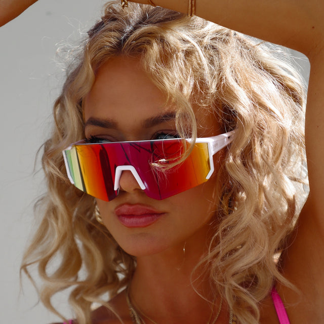 customer content - blonde woman with wavy hair wearing white sport diff sunglasses with red orange mirror lenses