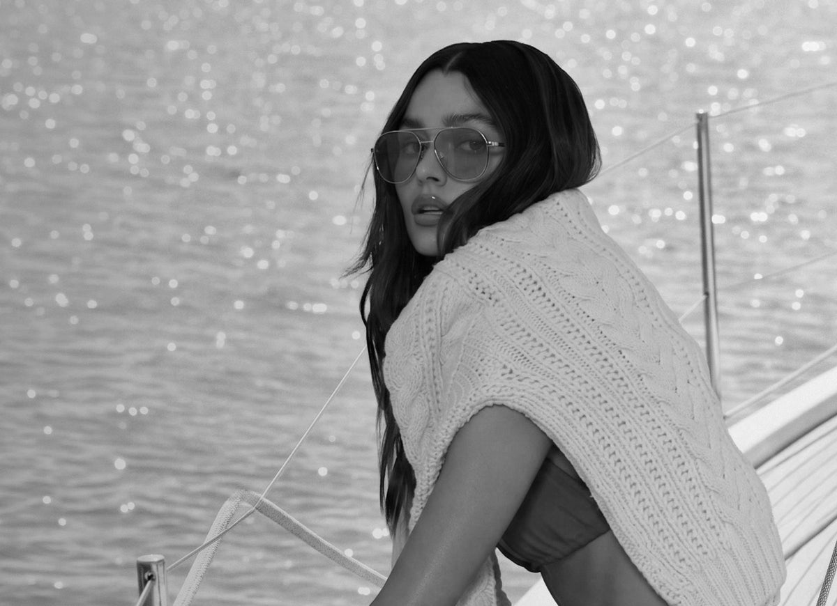female on a beach wearing beach riot x diff eyewear the coast in red with navy lenses