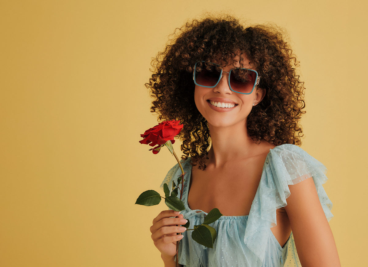 belle disney princess x diff eyewear frame on model with yellow background holding red rose