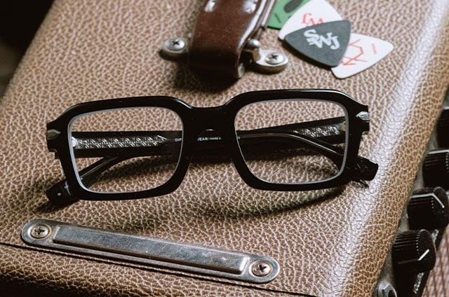 still life of diff eyewear x stephen wilson jr calico creak square sunglasses in black laying on a amp