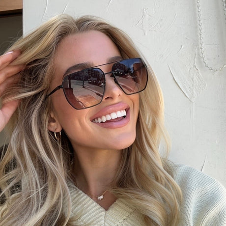 shelby hunstad wearing diff eyewear Berkely navigator sunglasses with a black metal frame and twilight gradient lenses