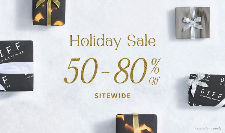 Young woman wearing pink glasses leaning her head against her hand as the sunlight through the window hits her face