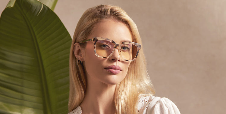 Woman standing in front of old building in downtown LA adjusting her black-framed Bella XS blue light blocking technology glasses