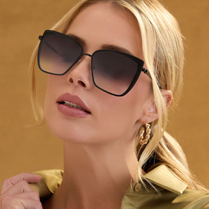 lifestyle - female wearing diff eyewear grace cat eye sunglasses with a matte black frame and grey gradient sharp lenses angled view