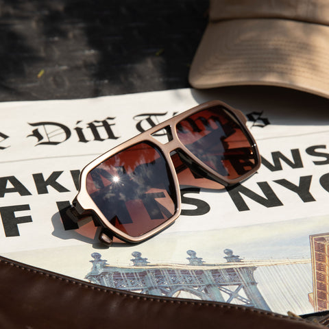 flat lay - diff eyewear featuring the cameron navigator sunglasses with a moscow mule frame and brown gradient lenses laying on a newspaper