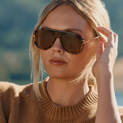 lifestyle - blonde female wearing diff eyewear cleo oversized aviator sunglasses with a rich tortoise frame, gold temples and brown gradient polarized lenses angled view