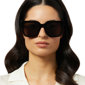 on model - female wearing iconica diff eyewear thea square oversized sunglasses with a black acetate frame and grey lenses front view