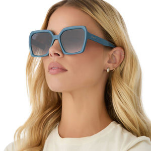 on model - female wearing diff eyewear featuring the sloane square sunglasses with a deep space blue frame and grey gradient lenses angled view