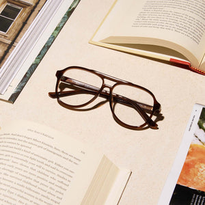 lifestyle - diff eyewear featuring the tatum aviator blue light readers with a whiskey crystal frame laying on a desk