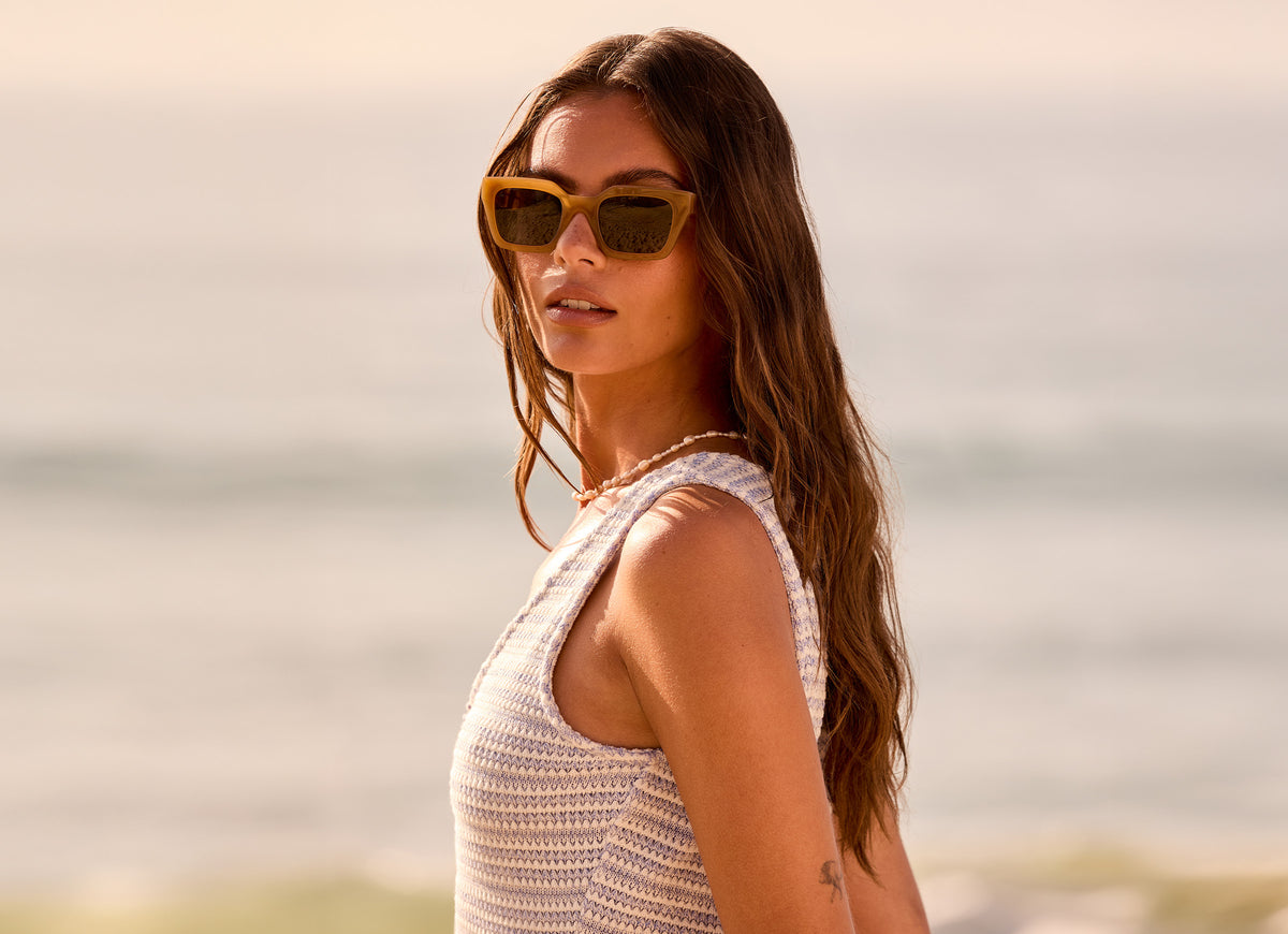 female on the beach wearing Travis Mathew x DIFF Eyewear solana in caramel with a g15