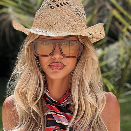 lifestyle - ashley smith blonde wearing bridgeless sunglasses with colored tinted lens and straw hat resortwear