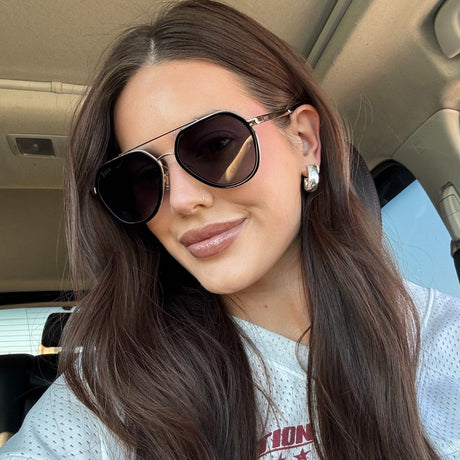 brunette wearing black aviator sunglasses in car