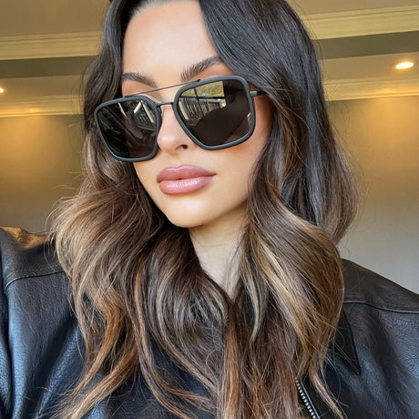 brunette wearing black leather jacket and black navigator sunglasses