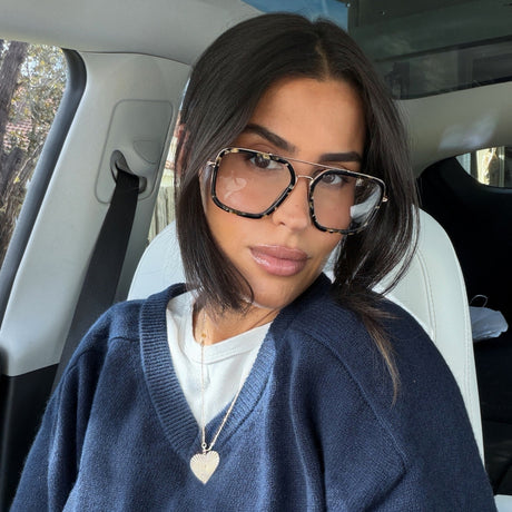 lifestyle - rachel bonskine brunette influencer in fall fashion in car with navy oversized v-neck knit sweater with white tee under and tortoise print eyeglasses