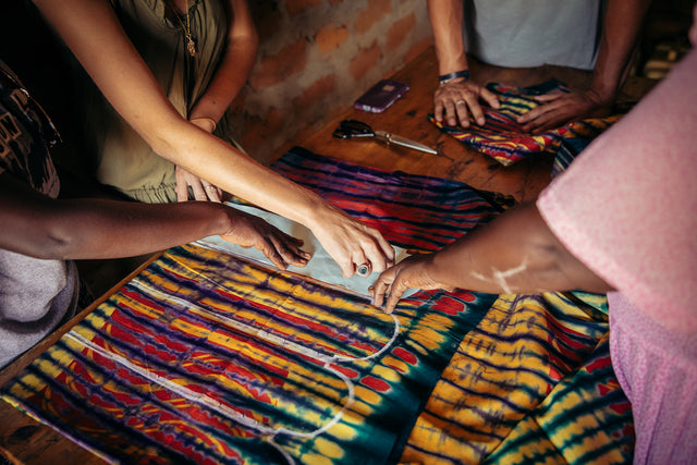 Women working together in a brick room drawing Kitenge pouch pattern on fabric