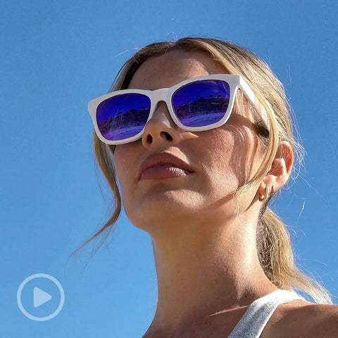 Young woman at the beach wearing DIFF Storm white sunglasses with purple lenses