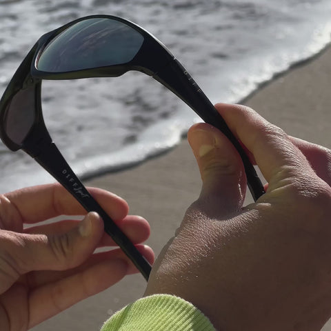 video of emale on the beach wearing diff sport lightning wrap sunglasses with a matte black frame and peach mirror polarized lenses front view