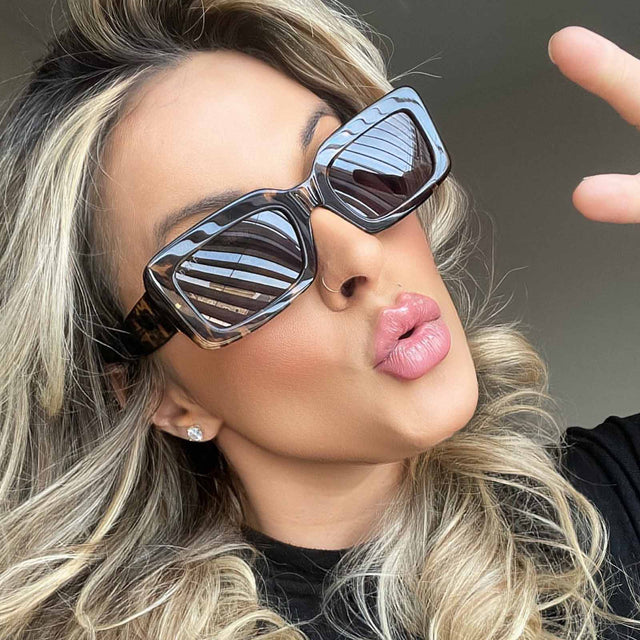 customer content - blonde female blowing a kiss while wearing diff eyewear indy rectangular sunglasses with a espresso tortoise acetate frame and grey lenses